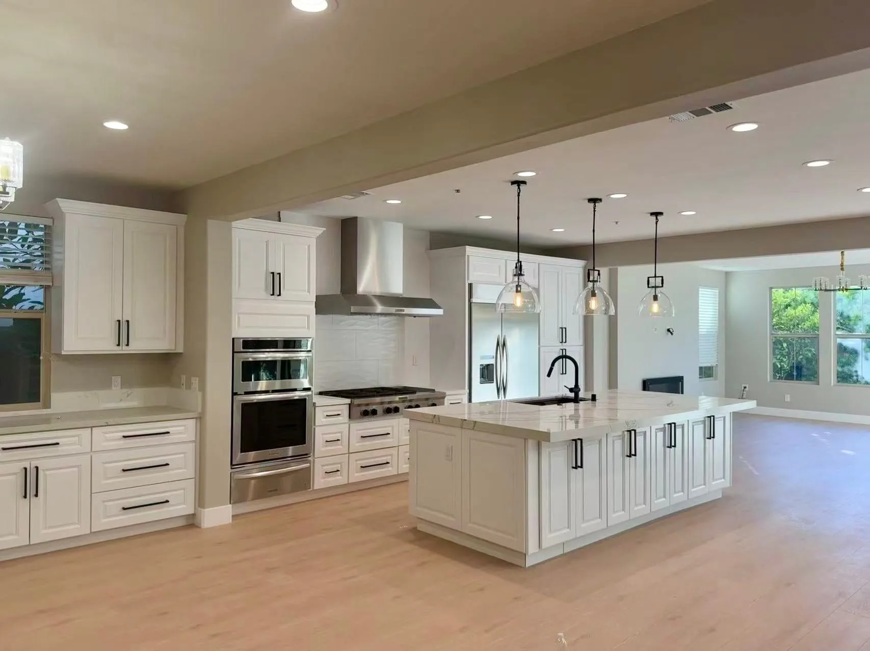 White raised-panel kitchen with a double wall oven, pro range, and a large island