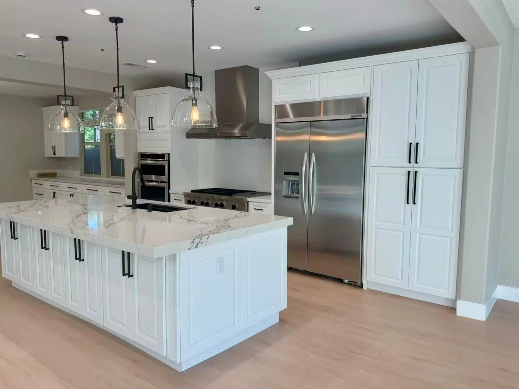White raised-panel kitchen with an island, built-in refrigerator, and a pantry wall