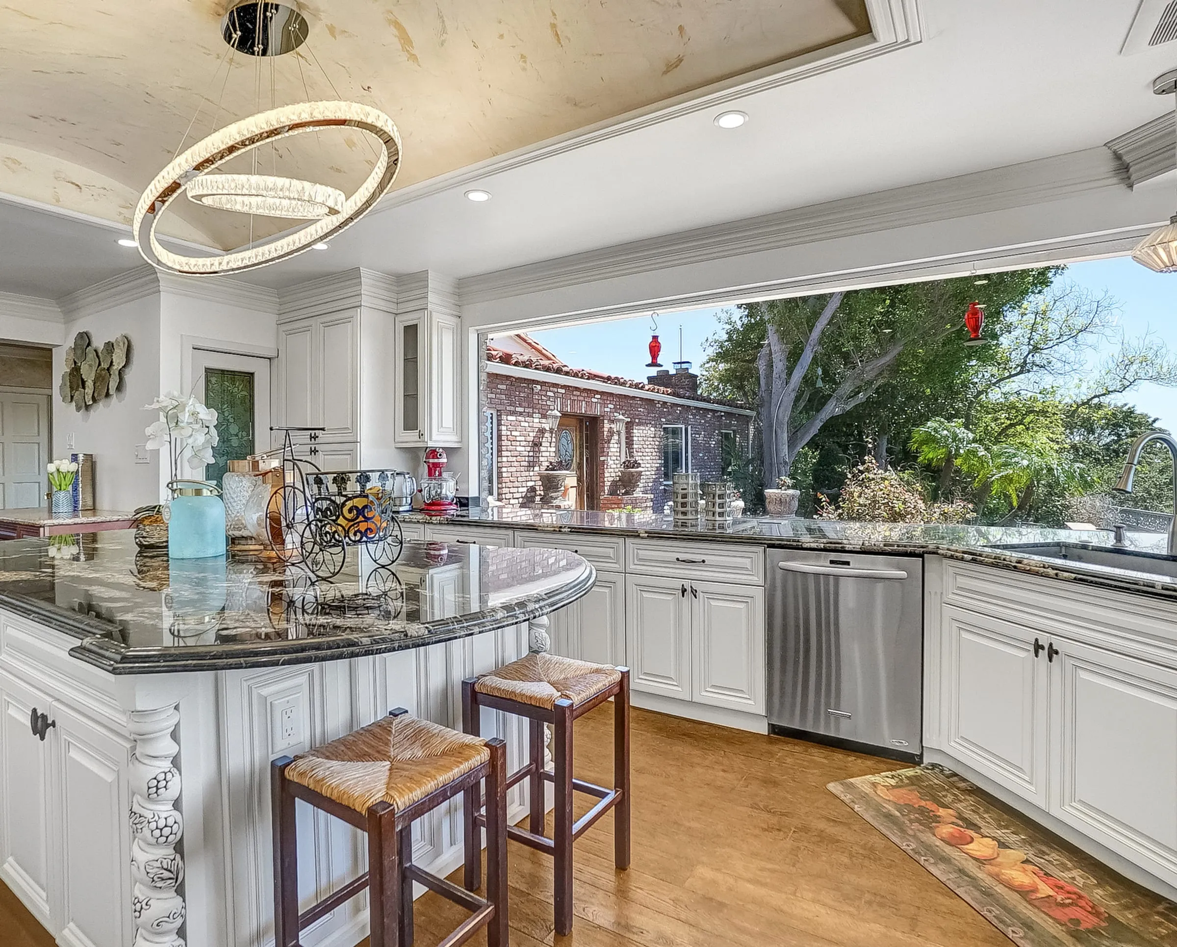 White glazed island with rush stools, a ring chandelier, and a garden window