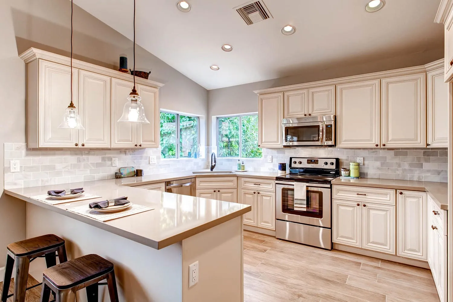 Antique White raised-panel kitchen with a peninsula, bar seating, and a vaulted ceiling