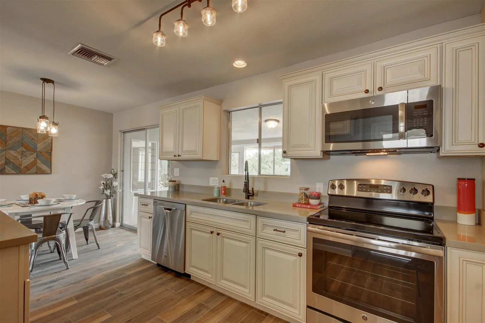 Antique White galley kitchen with gray counters, stainless range, and a dining nook beyond