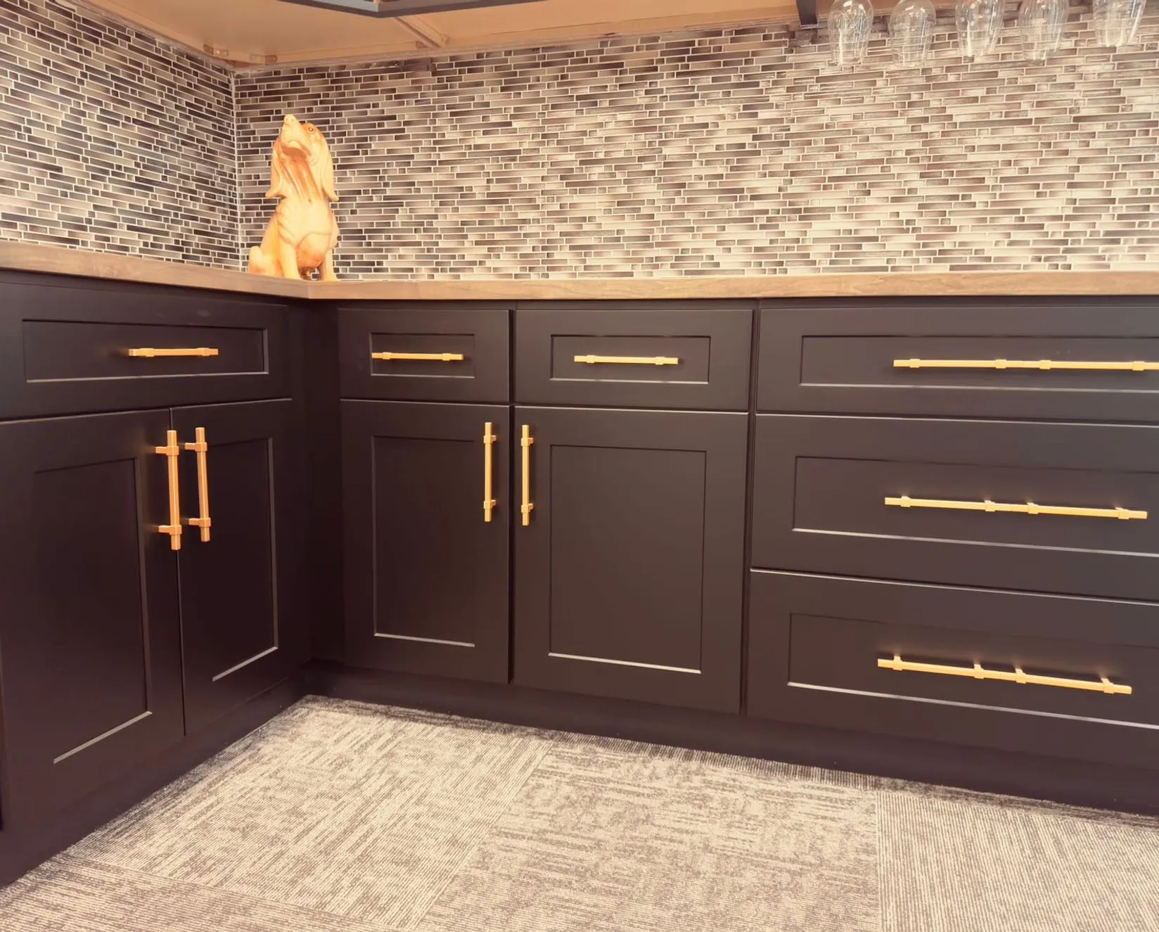 Black shaker base cabinets with gold bar pulls and a mosaic backsplash