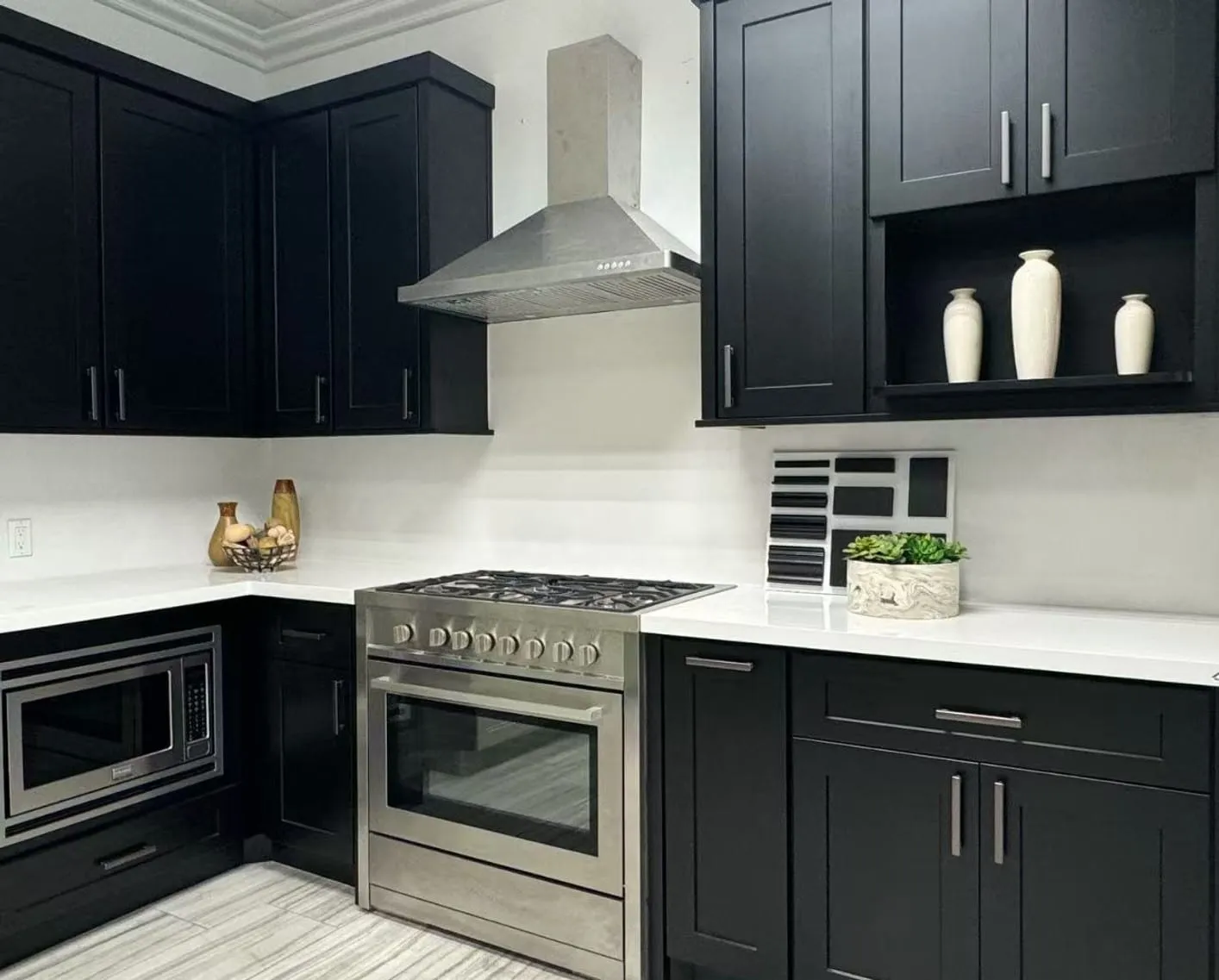 Black shaker kitchen with white quartz and a stainless range and hood