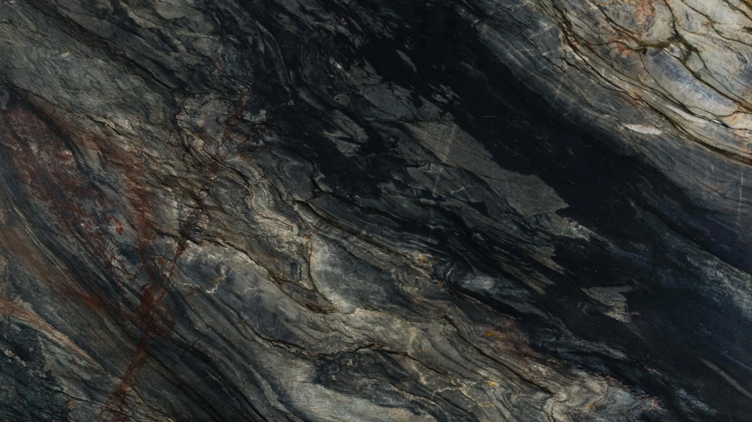 Tempest Blue quartzite slab, near black with blue-grey movement and a rust red vein