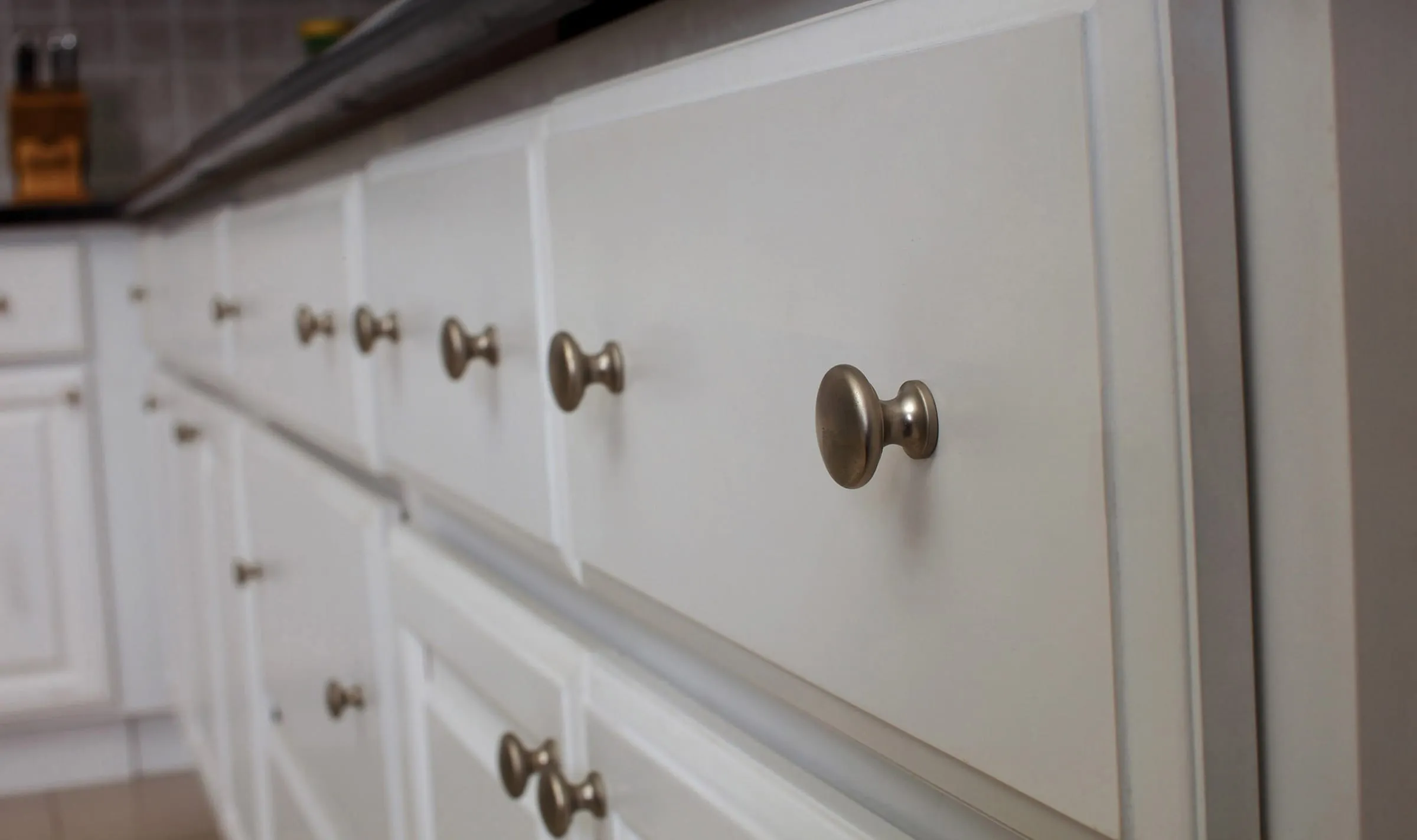 Close view of Classic White drawer fronts with antique-brass knobs