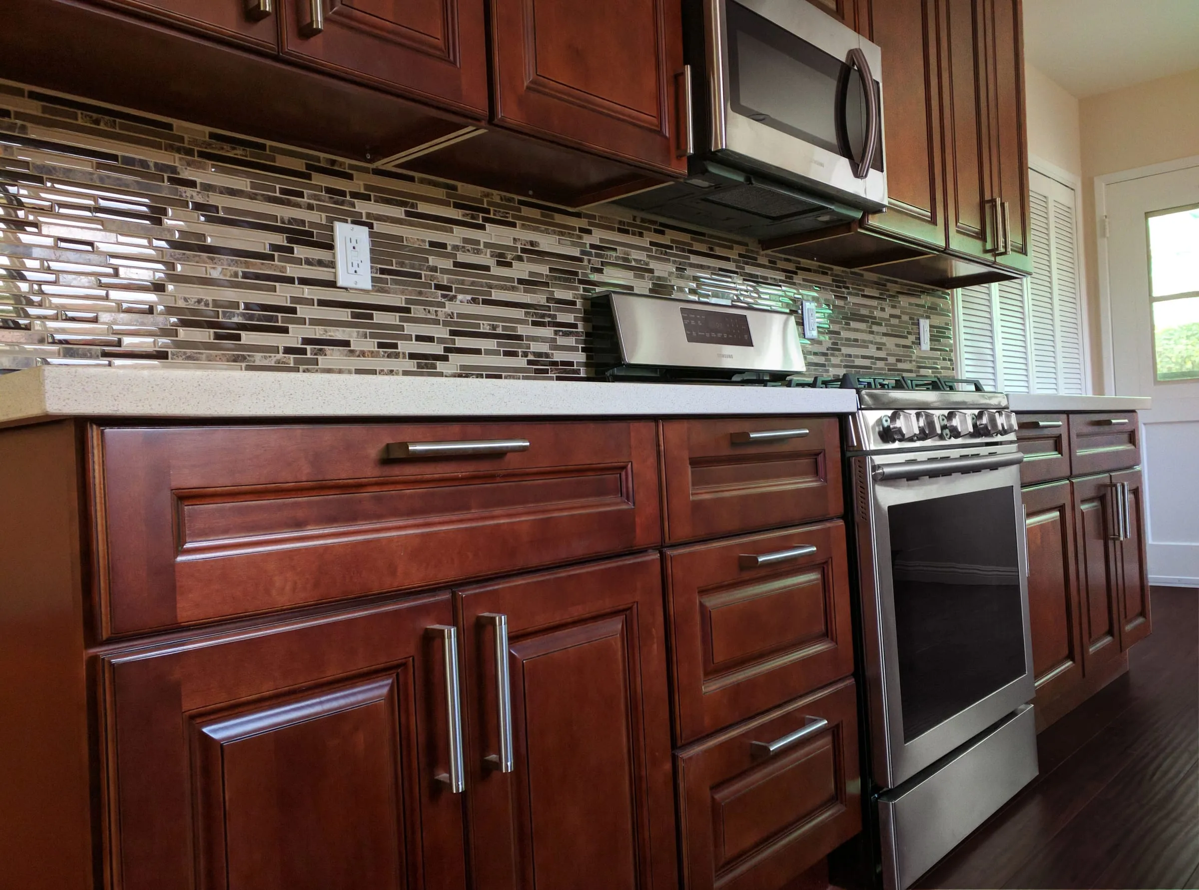 Dark Cherry base cabinets with a glass mosaic backsplash and a stainless range
