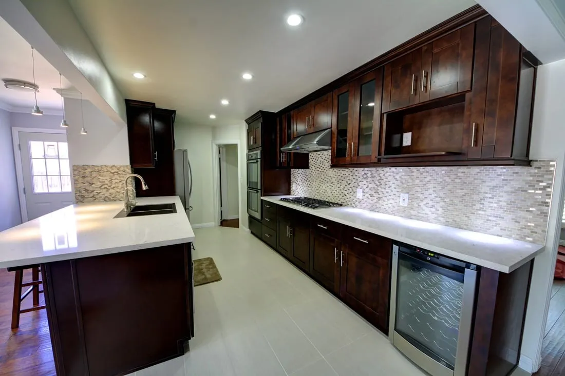 Espresso shaker galley kitchen with white quartz counters, stainless wall oven, and a mosaic backsplash