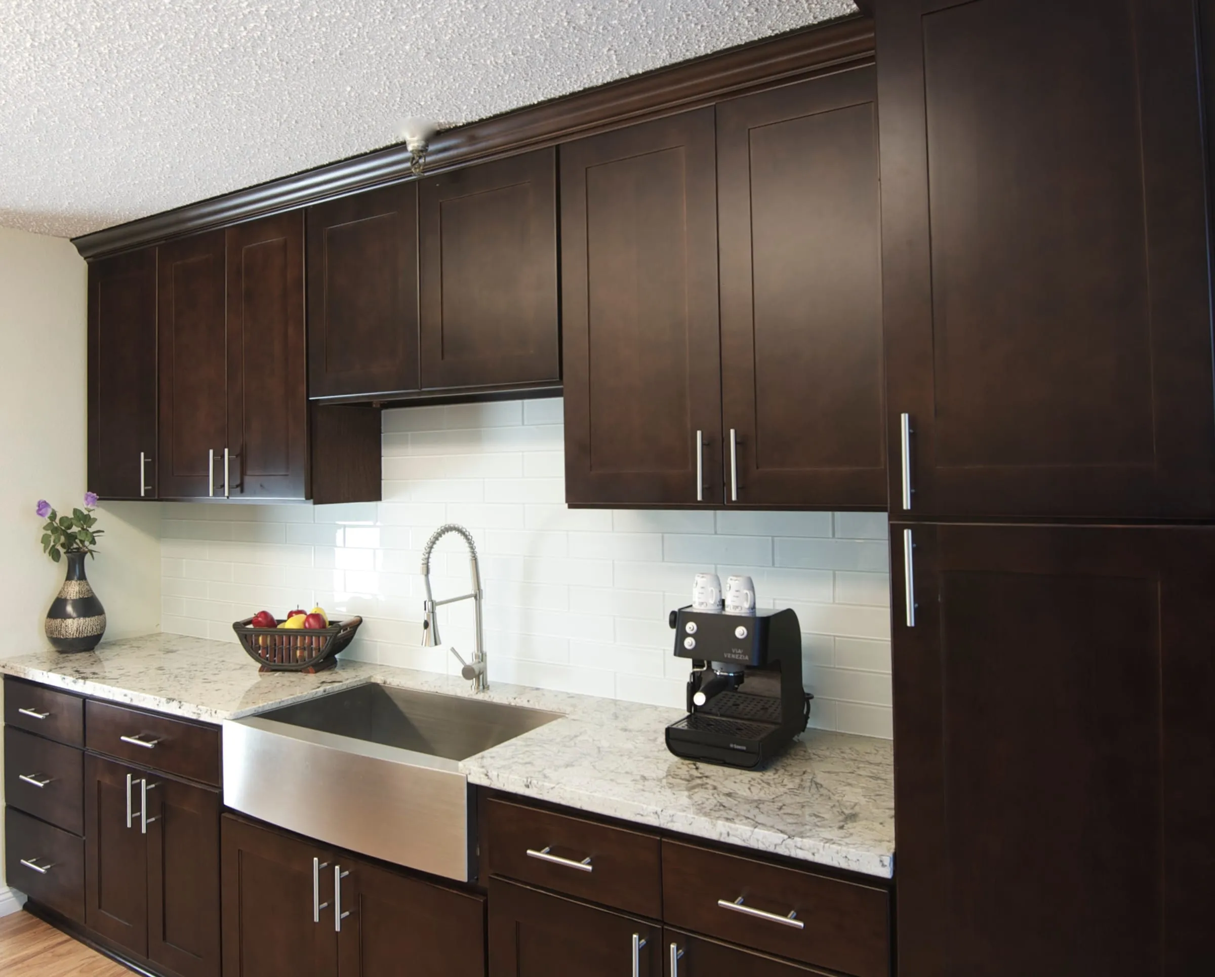 Espresso kitchen wall run with white subway tile and a farmhouse sink