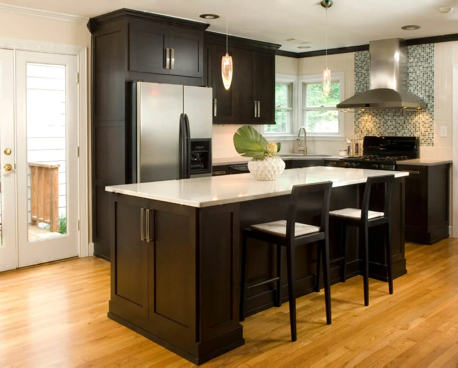 Espresso kitchen with an island, two stools, and a white quartz top