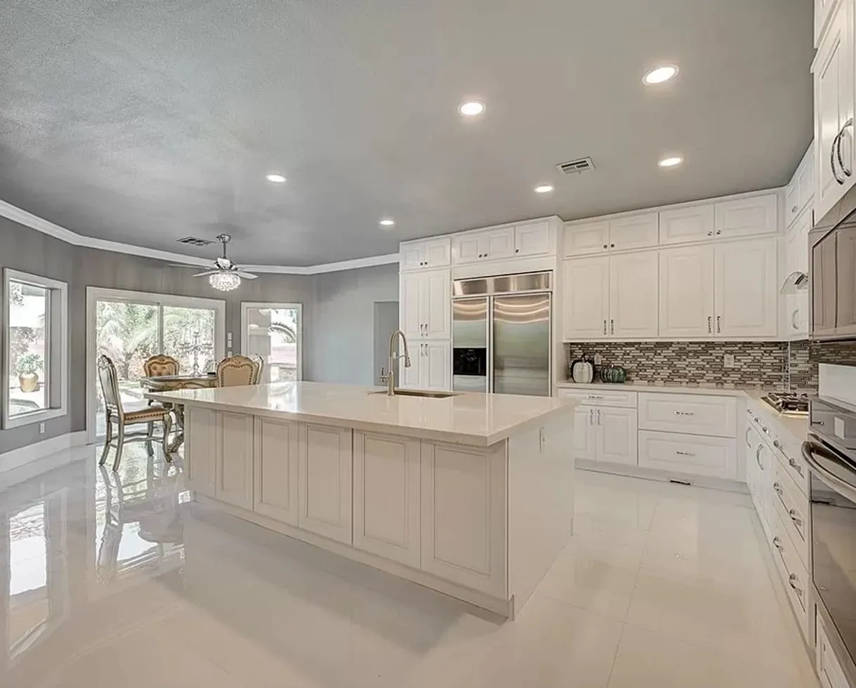 Large all-white kitchen with an island and a glossy tile floor