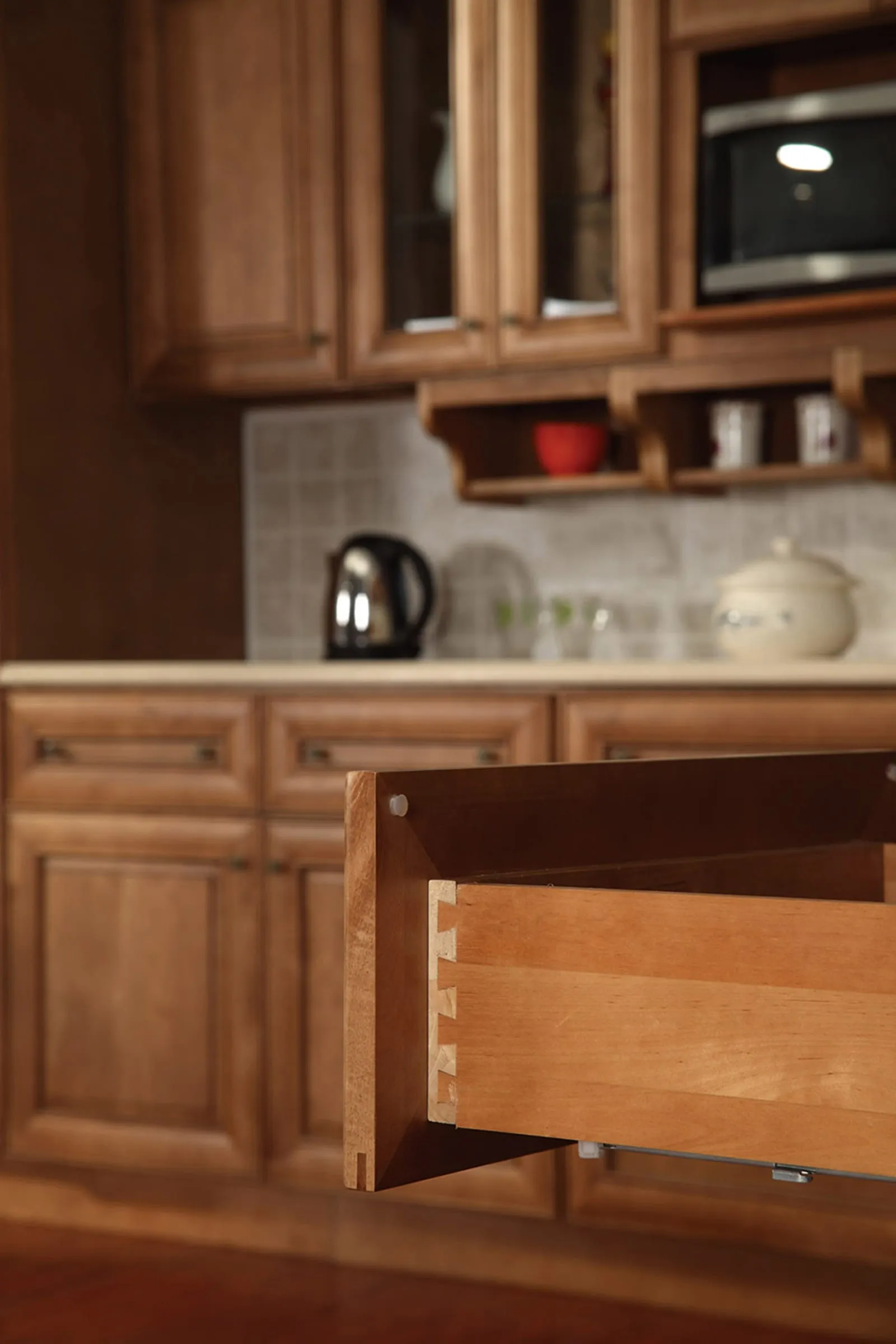 Dovetail solid-wood drawer box pulled open in a ginger-stained kitchen