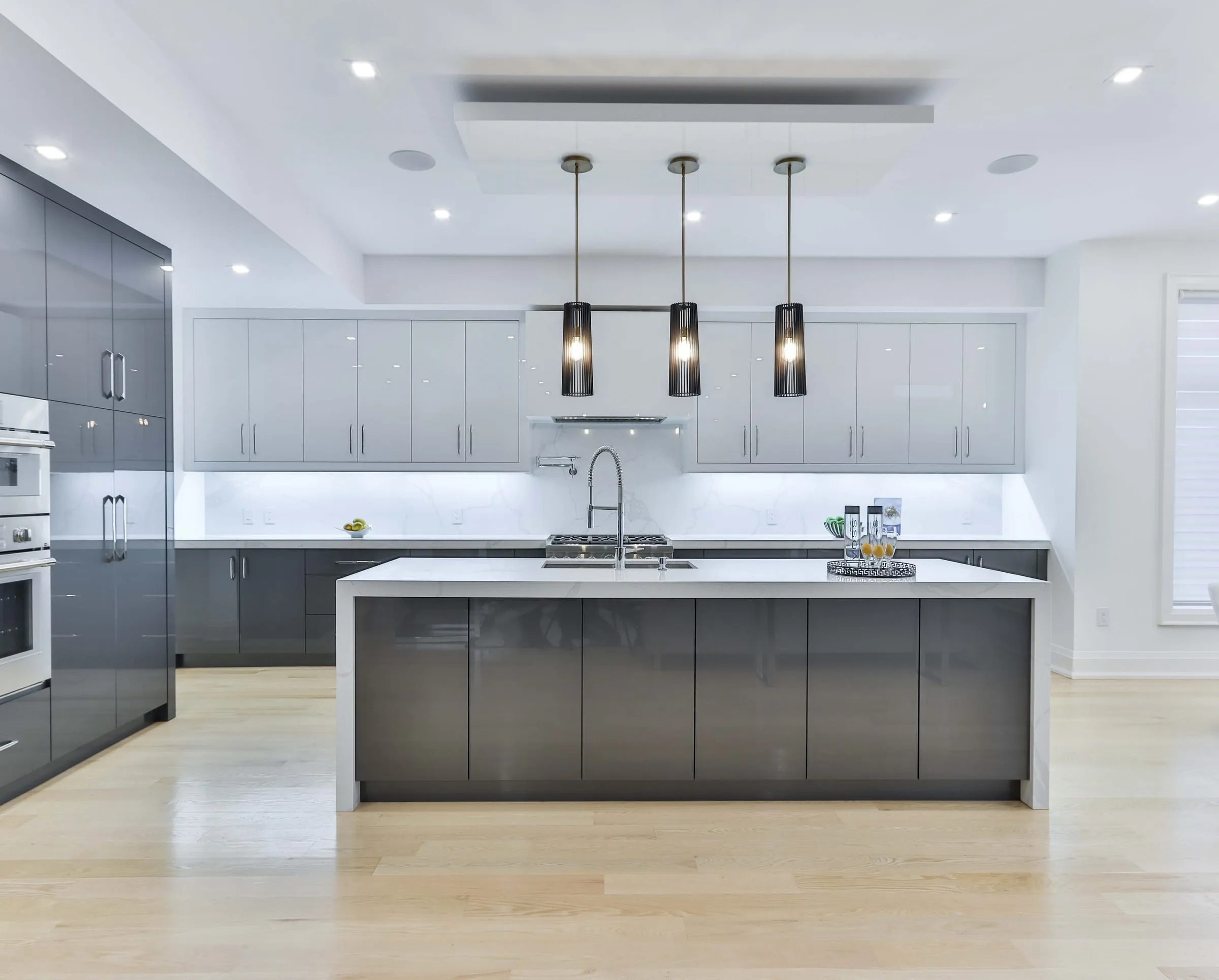 Grey high-gloss kitchen with an island and three black pendants