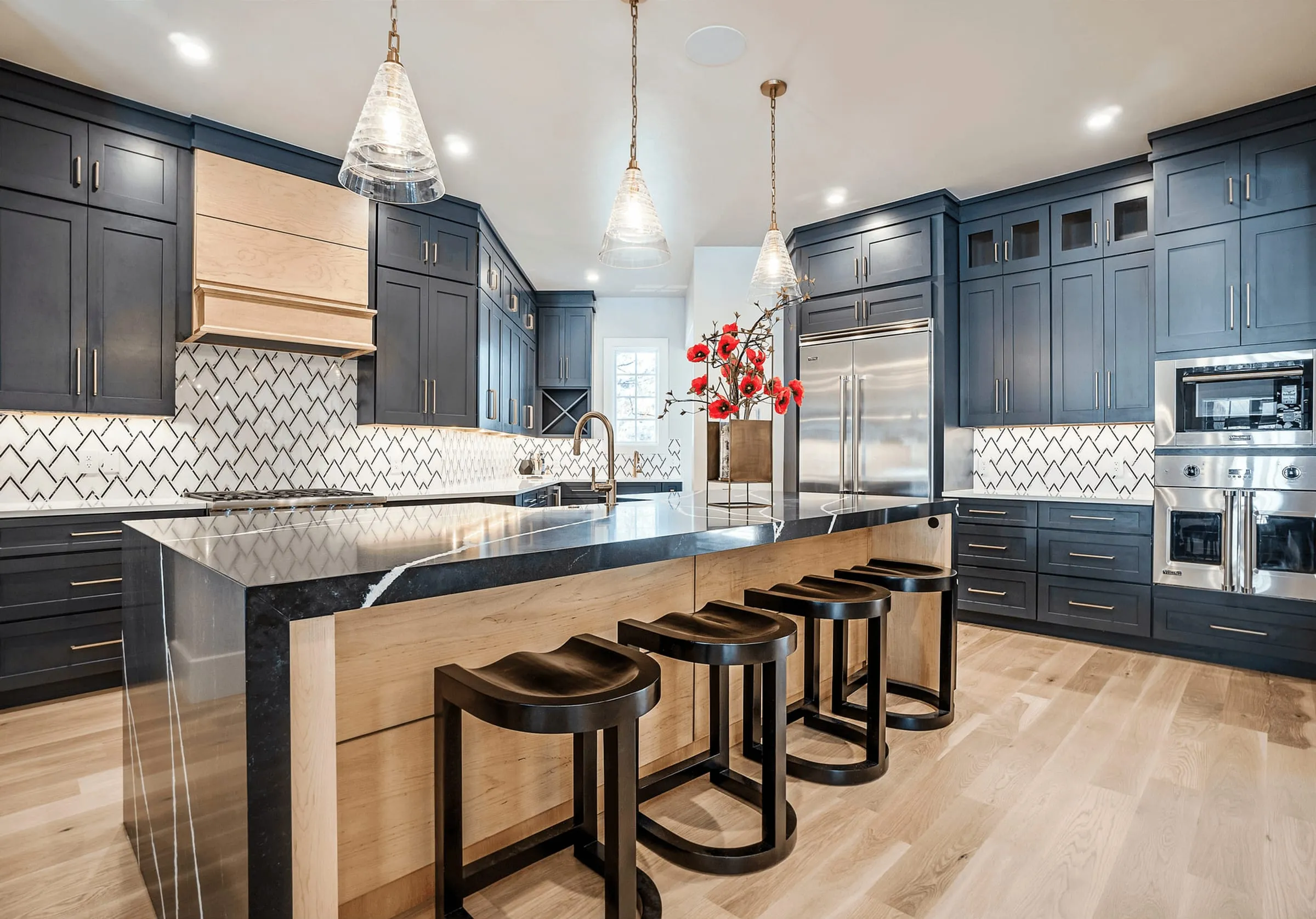 Charcoal-grey shaker kitchen with a wood island, red poppies, and black stools