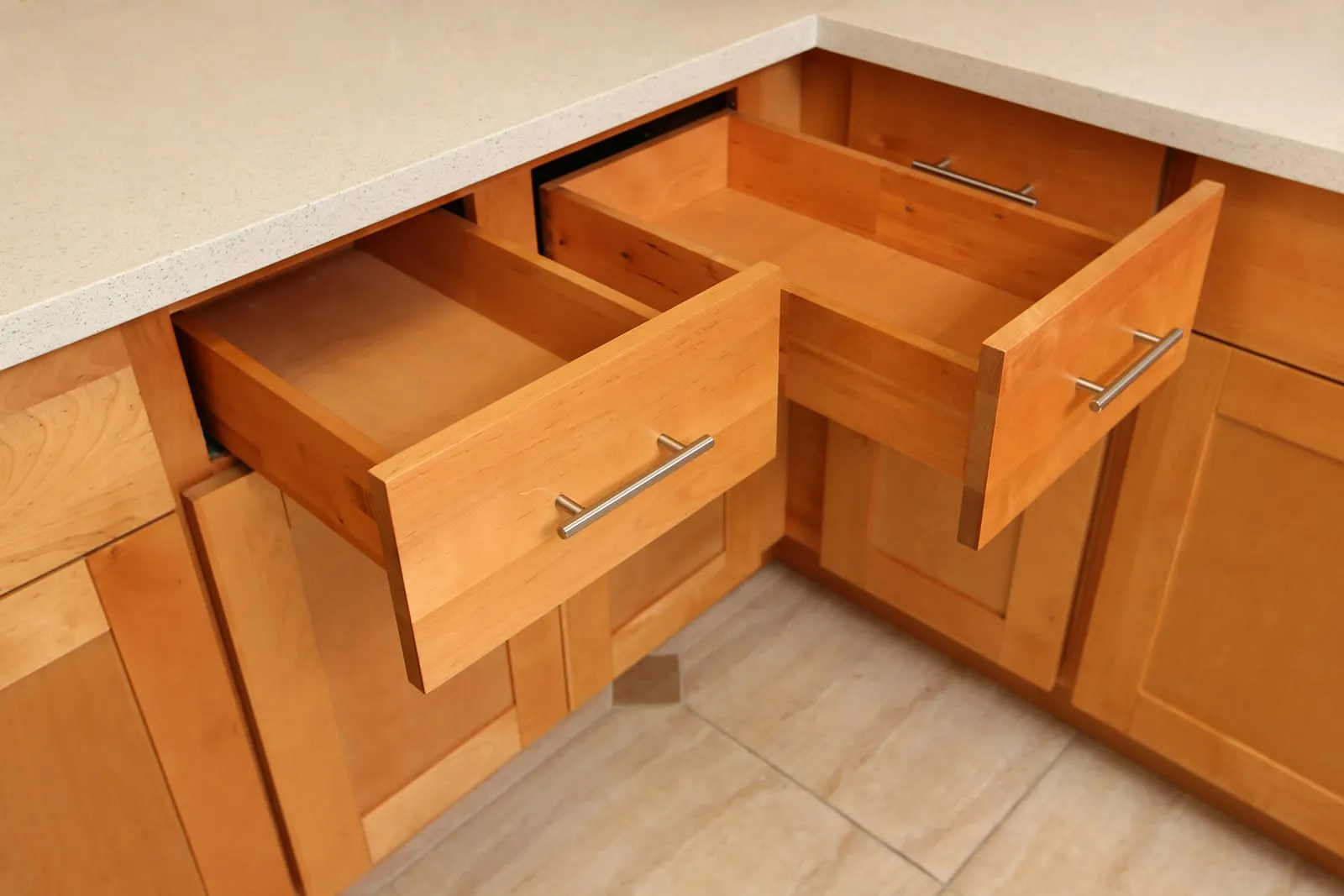 Honey-stained corner base cabinets with drawers pulled open showing full-extension slides