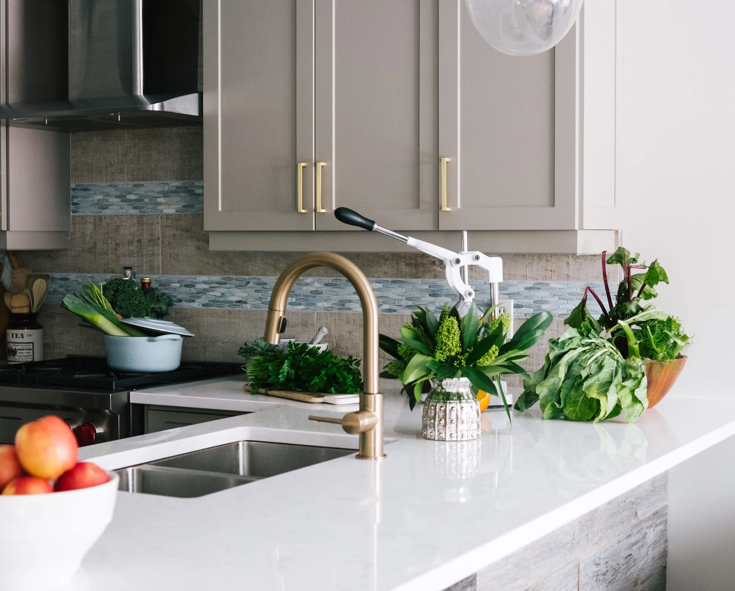 Warm-greige shaker kitchen close-up with a brass faucet and fresh produce
