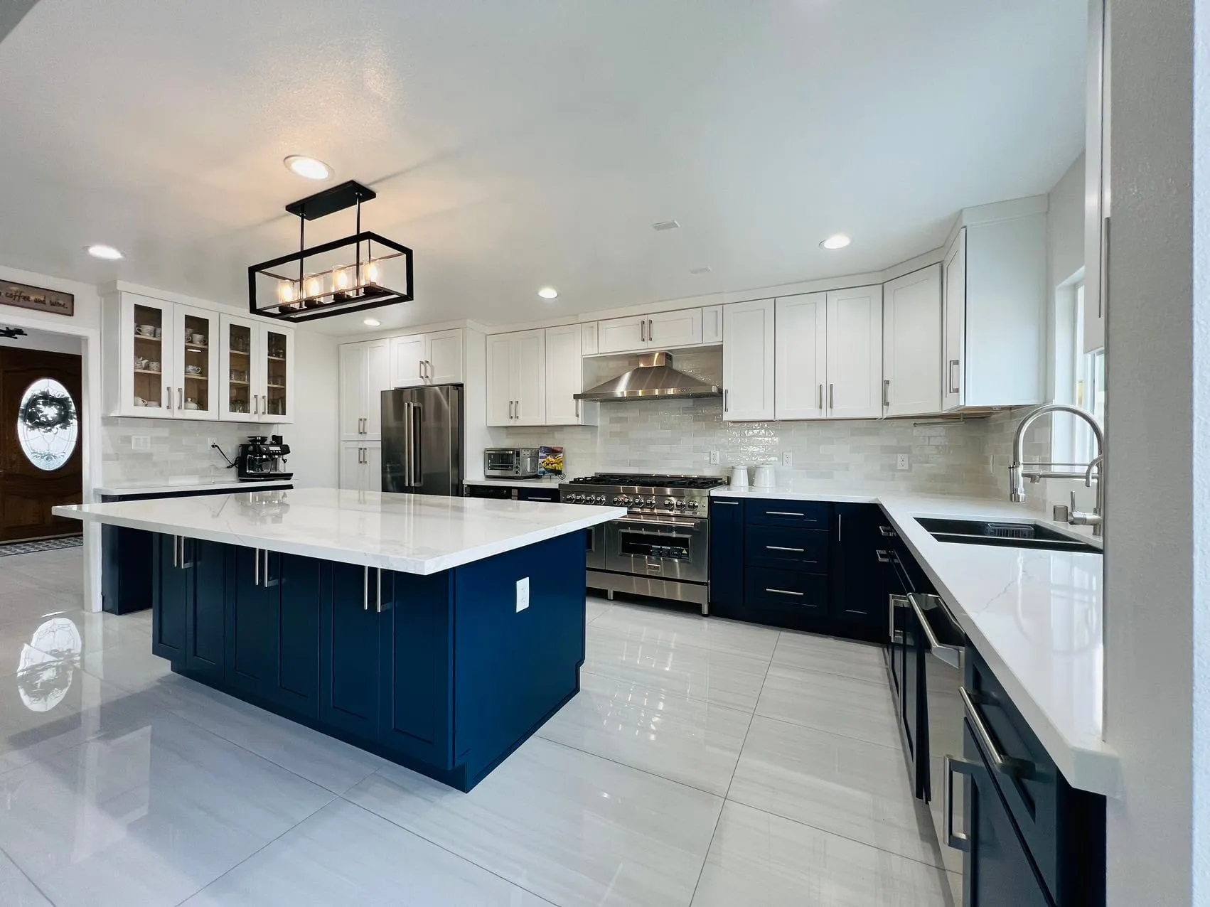 Navy blue shaker island and base cabinets paired with white shaker uppers and white quartz counters