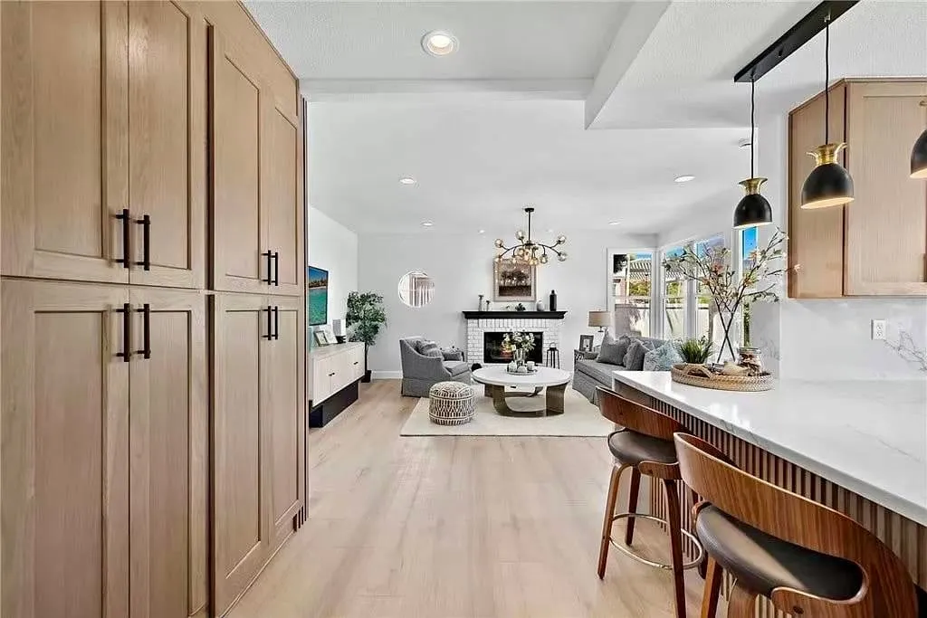 Oak kitchen peninsula opening to a living room with a fireplace