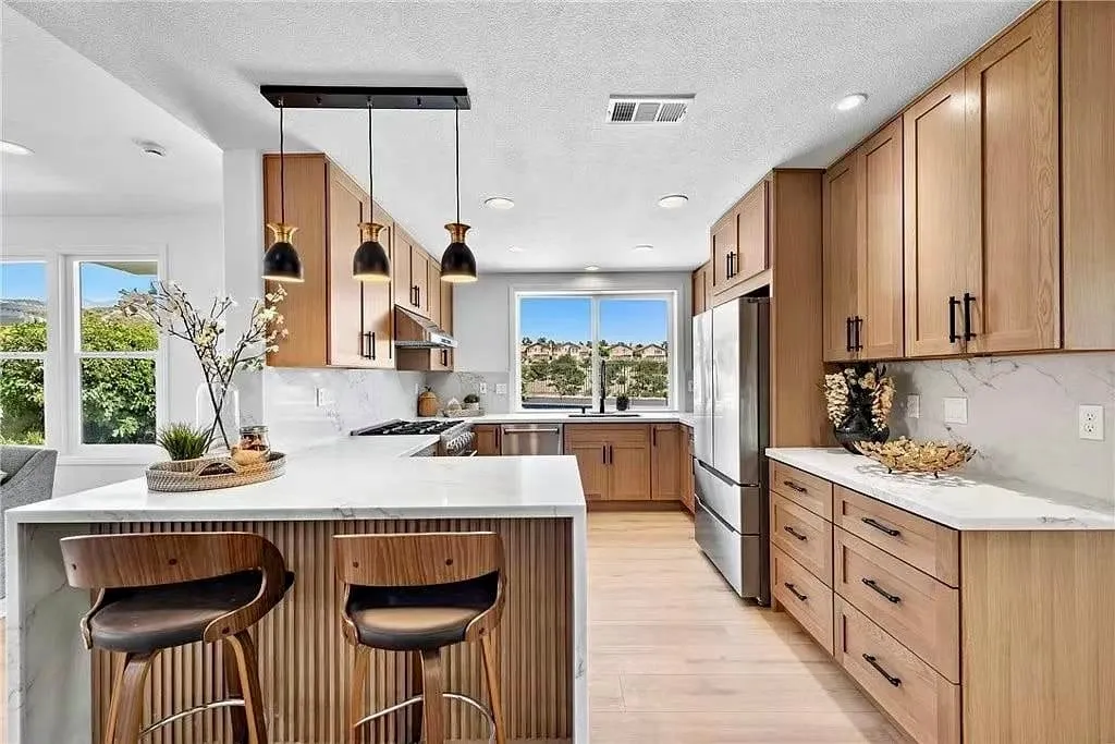 Oak shaker kitchen with a peninsula, barstools, and a window over the range