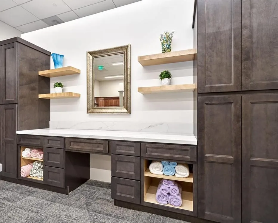 Grey-brown showroom vanity run with floating shelves and towels
