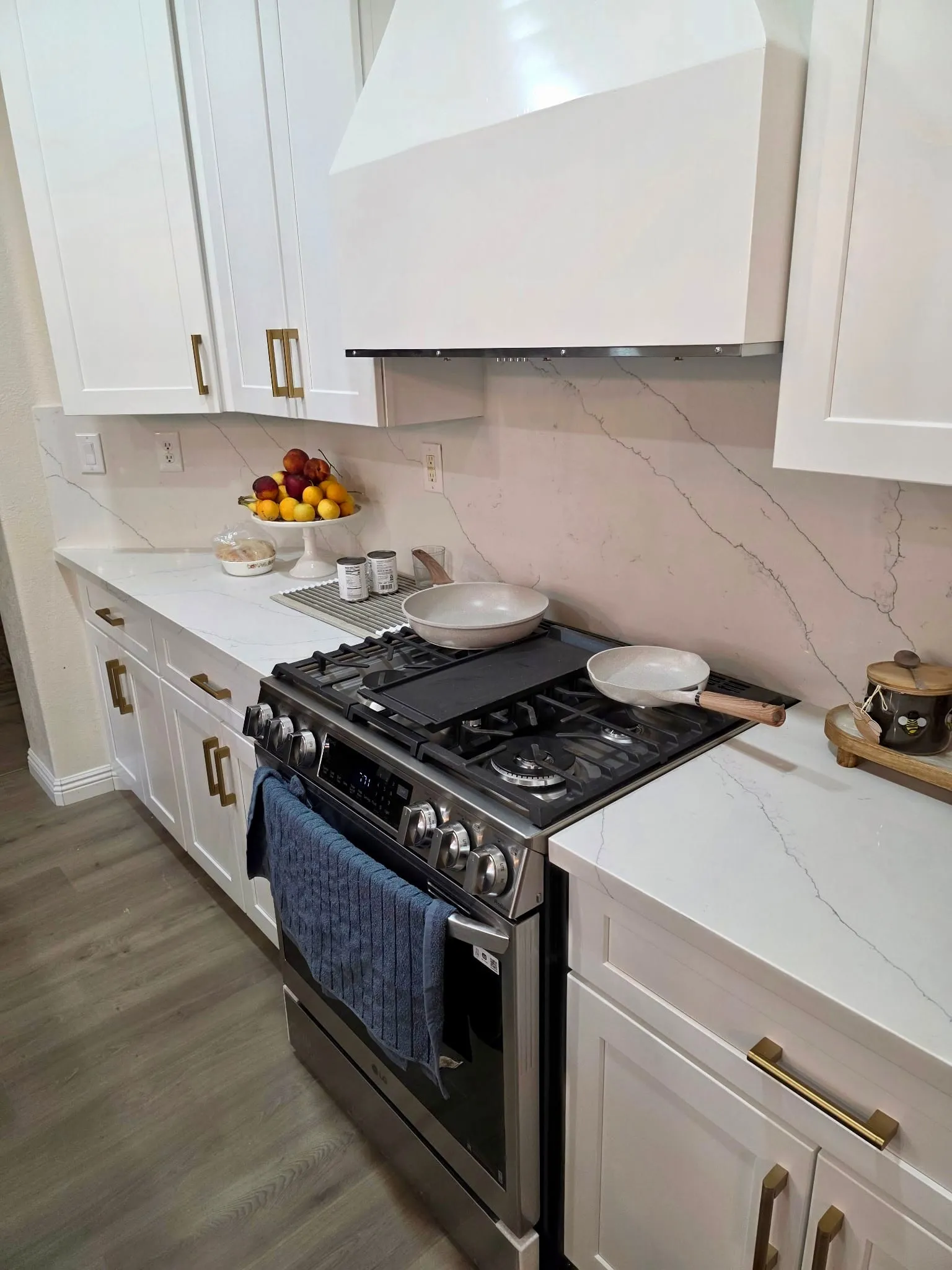 White shaker kitchen with a stainless gas range and a marble slab backsplash