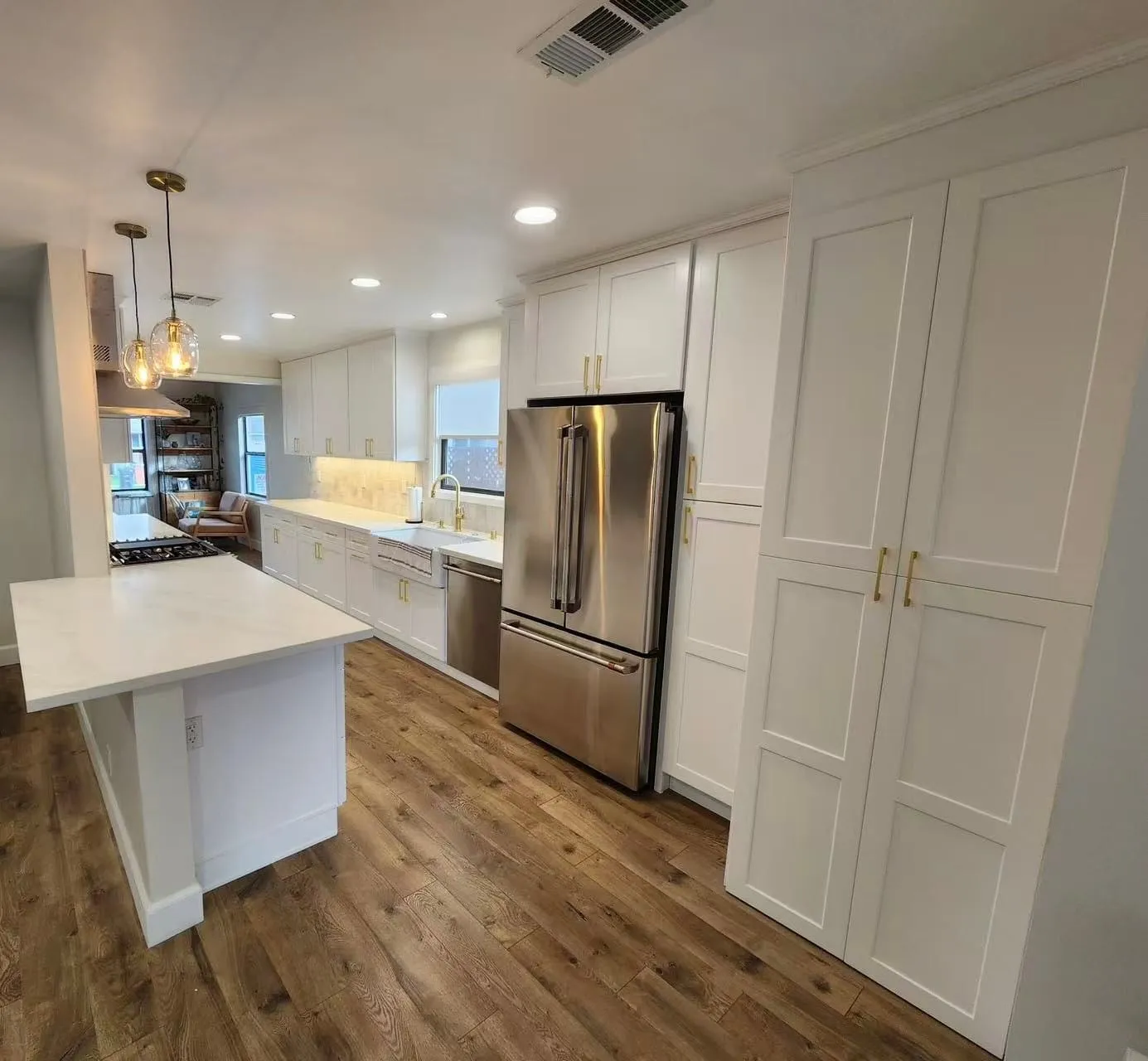 White shaker kitchen with a peninsula, floating shelves, and a pantry wall