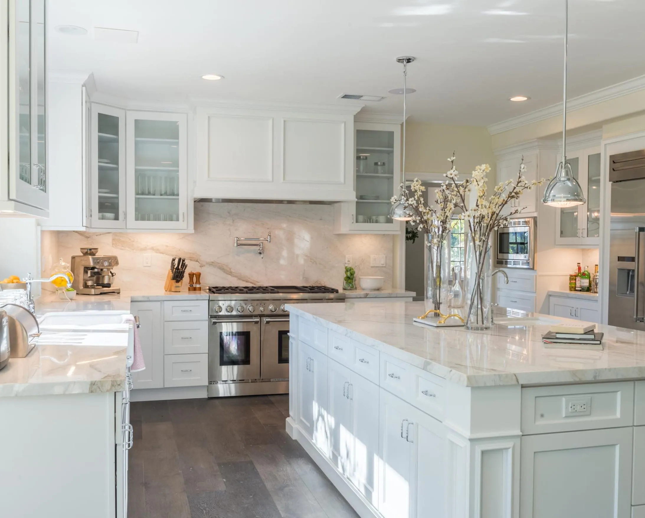 White kitchen with a marble backsplash and island and a professional stainless range